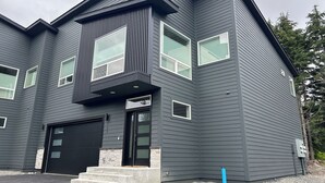 A modern two-story house with a black exterior, a garage, and a small porch.