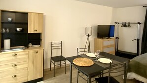 A compact room with a dining table, chairs, a TV, and a wardrobe. - Studio near city center (Verdun)