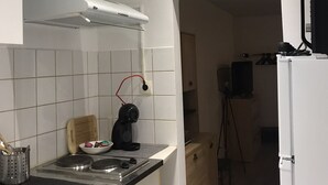 A modern kitchen with white cabinets, a gas stove, a kettle, and a white refrigerator. - Studio near city center (Verdun)