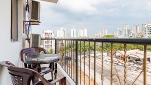 Varanda com mesa e cadeiras, vista para um horizonte urbano com edifícios altos.