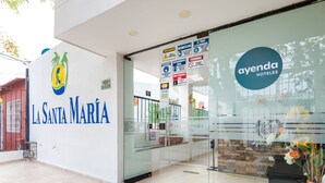 Exterior do Hotel La Santa María, com entrada de vidro e área de recepção visível.