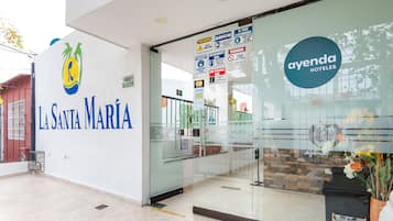 Exterior del Hotel La Santa María, con entrada de vidrio y recepción a la vista.