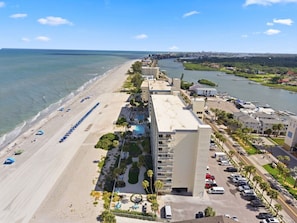 A coastal hotel with a beach view, a parking lot, and a marina.
