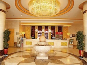 A lobby with a marble floor, a large fountain, a reception desk, and a chandelier. - Greentree Inn Jiuquan Century Plaza Hotel (Jiuquan)