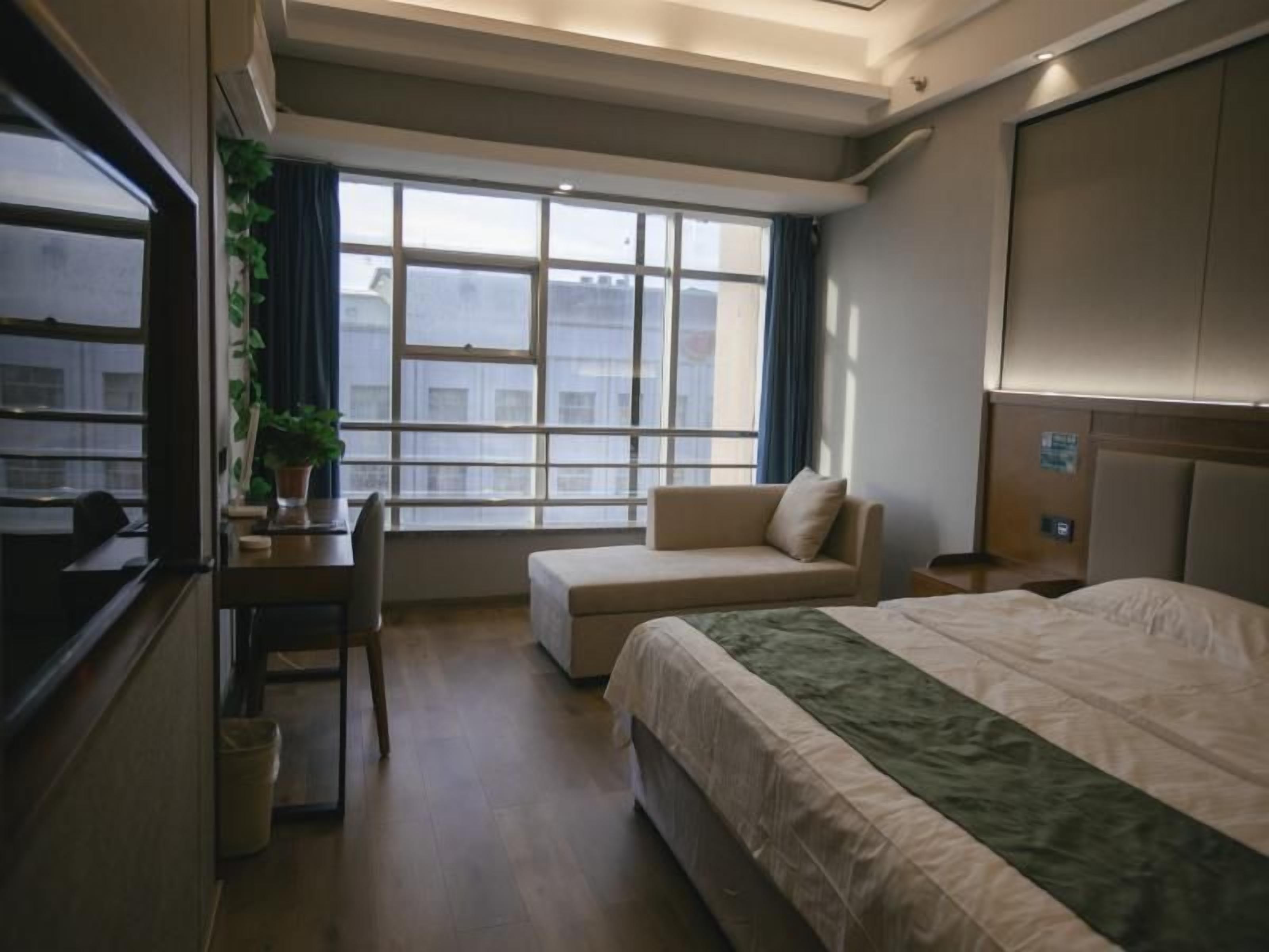 A hotel room with a bed, a sofa, a desk, and a window with a view.