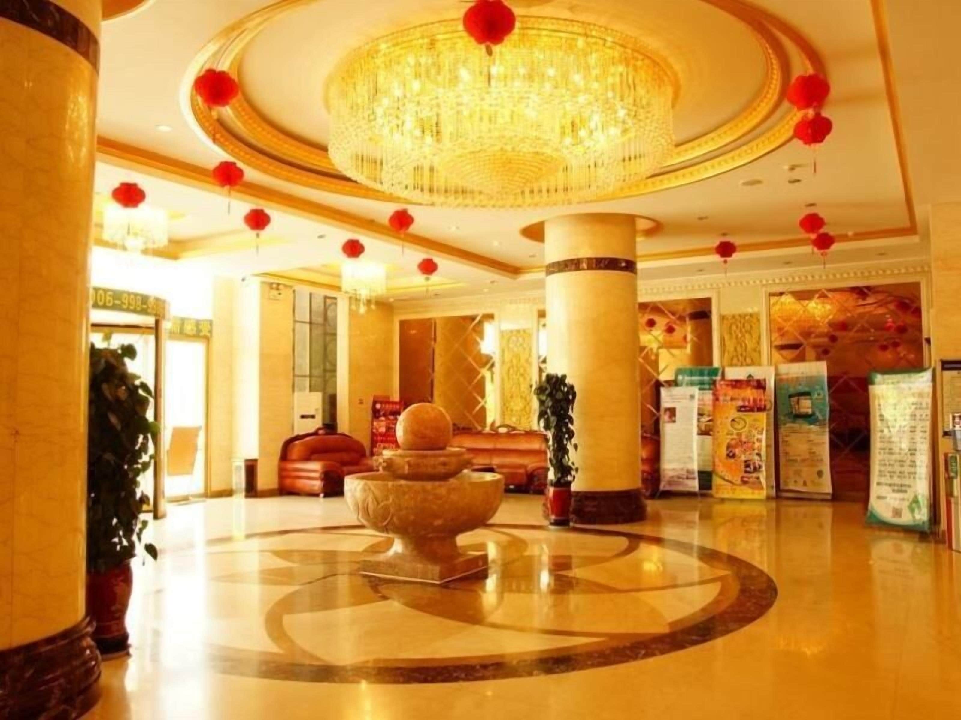 A lobby with a large chandelier, marble flooring, and red decorative elements.