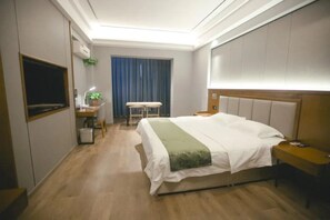 A hotel room with a bed, bedside table, desk with chair, and a TV. - Greentree Inn Jiuquan Century Plaza Hotel (Jiuquan)