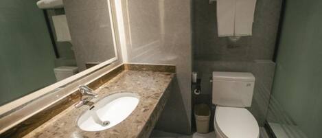 Un baño con lavamanos de mármol, inodoro y toallero.