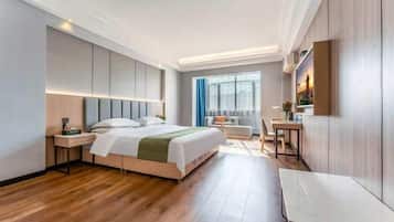 A modern hotel room with a large bed, a desk, a chair, and a window with curtains.