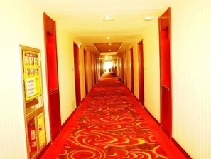 A hotel hallway with a red carpet, doors on both sides, and a poster on the left wall. - Greentree Inn Jiuquan Century Plaza Hotel (Jiuquan)