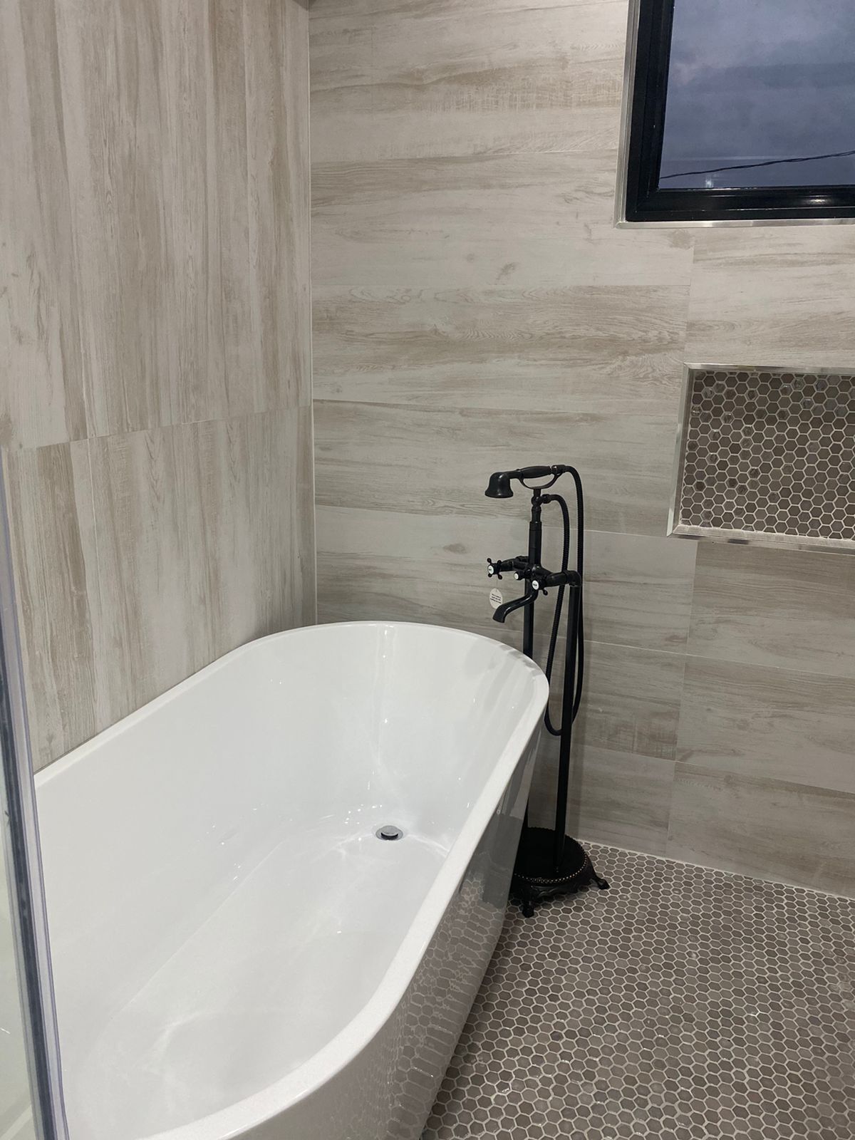 A modern bathroom with a freestanding bathtub, a showerhead, and a tiled floor.