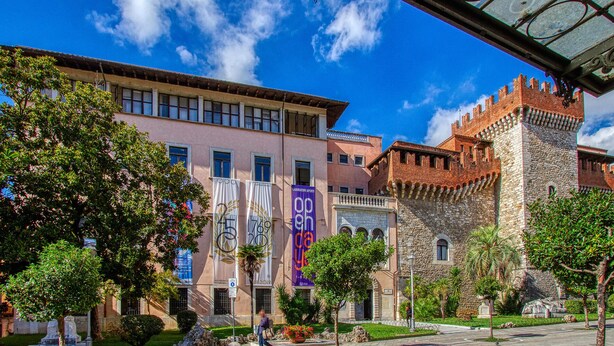 A historic building with a stone tower, modern buildings with banners, and a clear blue sky. - 2 bedroom lovely home in Sillano (Sillano)