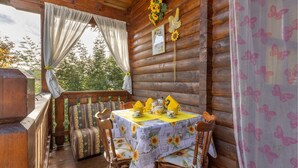 A wooden cabin with a dining area featuring a table set with yellow napkins, a floral tablecloth, and wooden chairs. - 2 bedroom lovely home in Sillano (Sillano)