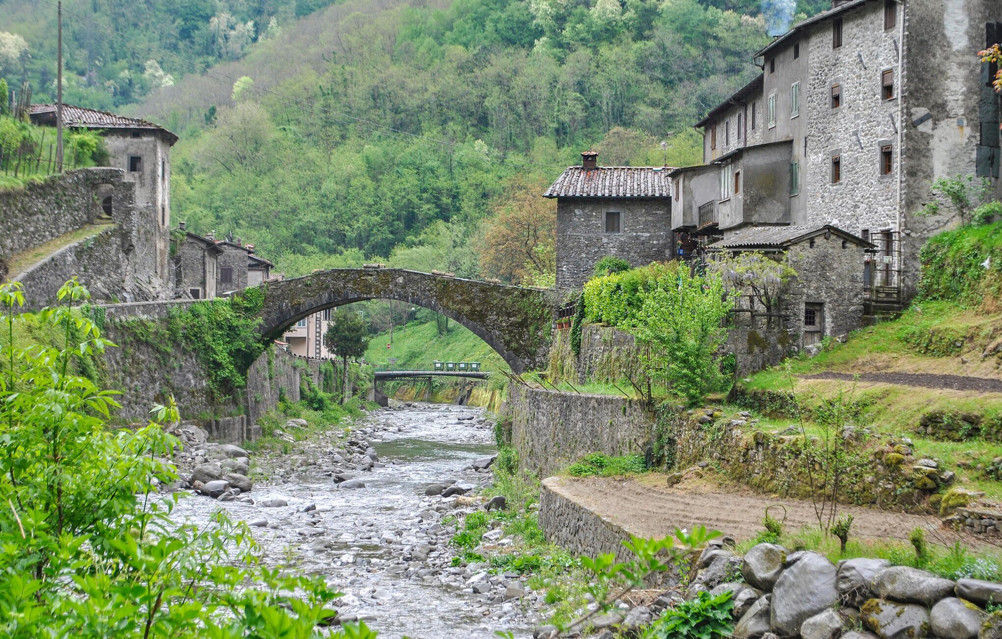 Un pont de pierre enjambant une rivière, entouré de bâtiments en pierre rustiques dotés d’une architecture traditionnelle.