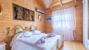 A wooden room with a bed, a chandelier, and artwork on the walls. - 2 bedroom lovely home in Sillano (Sillano)