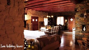 Un intérieur rustique avec des murs en pierre, des poutres en bois, un coin repas et une cheminée.