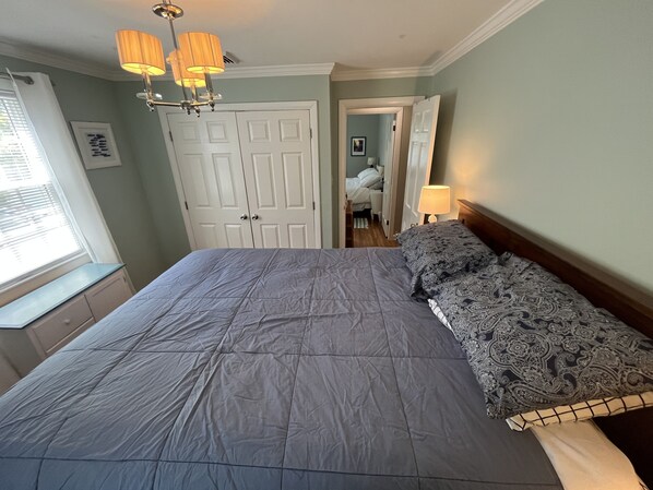 Une chambre à coucher avec un grand lit, une armoire, une fenêtre avec des stores et un lustre.
