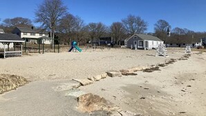 Een zandstrand met een speeltuin, een klein gebouw en een bewakerspost.