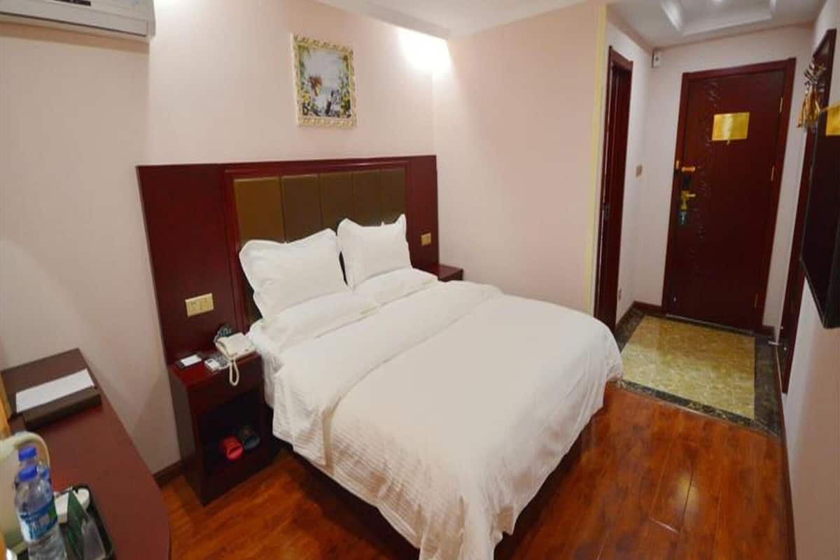 Une chambre d’hôtel comprenant un lit, une table de chevet et un bureau avec une chaise.