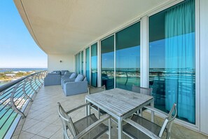 Uma varanda com mesa, cadeiras, um sofá e vista para o mar.