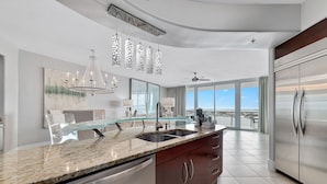Una cocina moderna con encimeras de granito, electrodomésticos de acero inoxidable y una isla grande con cubierta de vidrio.
