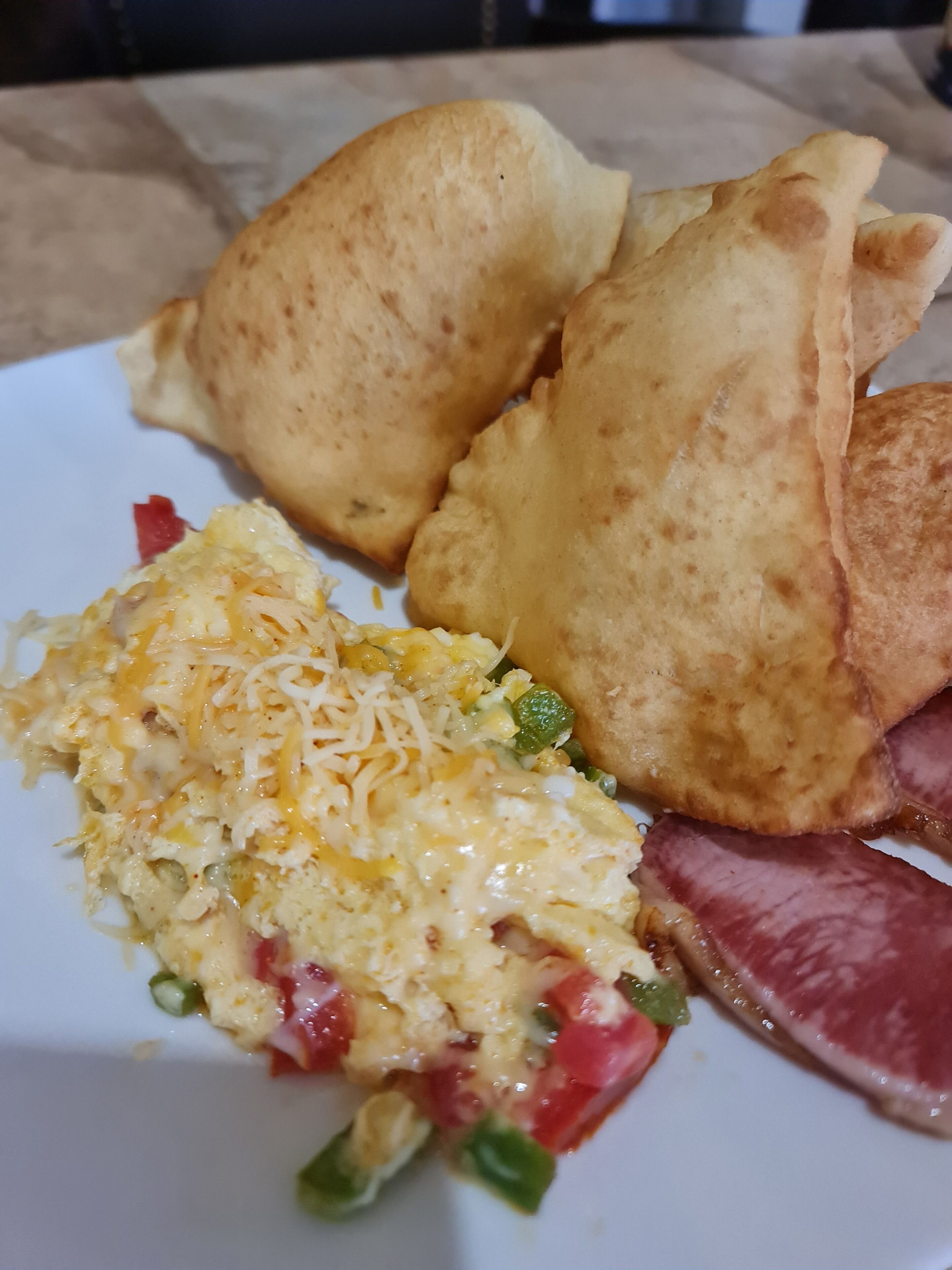 Um prato com ovos mexidos, queijo, fiambre e dois ovos fritos.