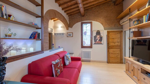 Un salon chaleureux avec un canapé rouge, des étagères en bois et un téléviseur.