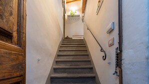 Un escalier avec une rampe, un luminaire fixé au mur et une petite plante au sommet.