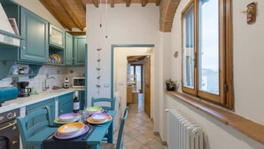 Une cuisine avec des meubles de couleur turquoise, une table à manger avec des assiettes colorées et une fenêtre donnant sur un beau paysage.