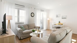 A modern living room with a sofa, a coffee table, and a dining table set for two.