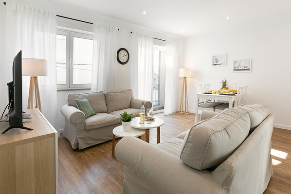 A modern living room with a sofa, a coffee table, and a dining table set for two.