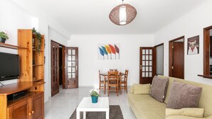 A modern living room with a flat-screen TV, wooden furniture, a white coffee table, and a beige sofa. - Relax in Foz - Shared Pool (Caldas da Rainha)