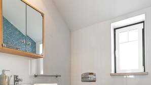 A bathroom with a wooden vanity, a toilet, a bidet, and a window. - Nazaré Boutique Apartment II (Nazaré)