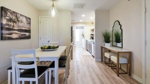 Cocina moderna con comedor, piso de madera y una lámpara colgante.