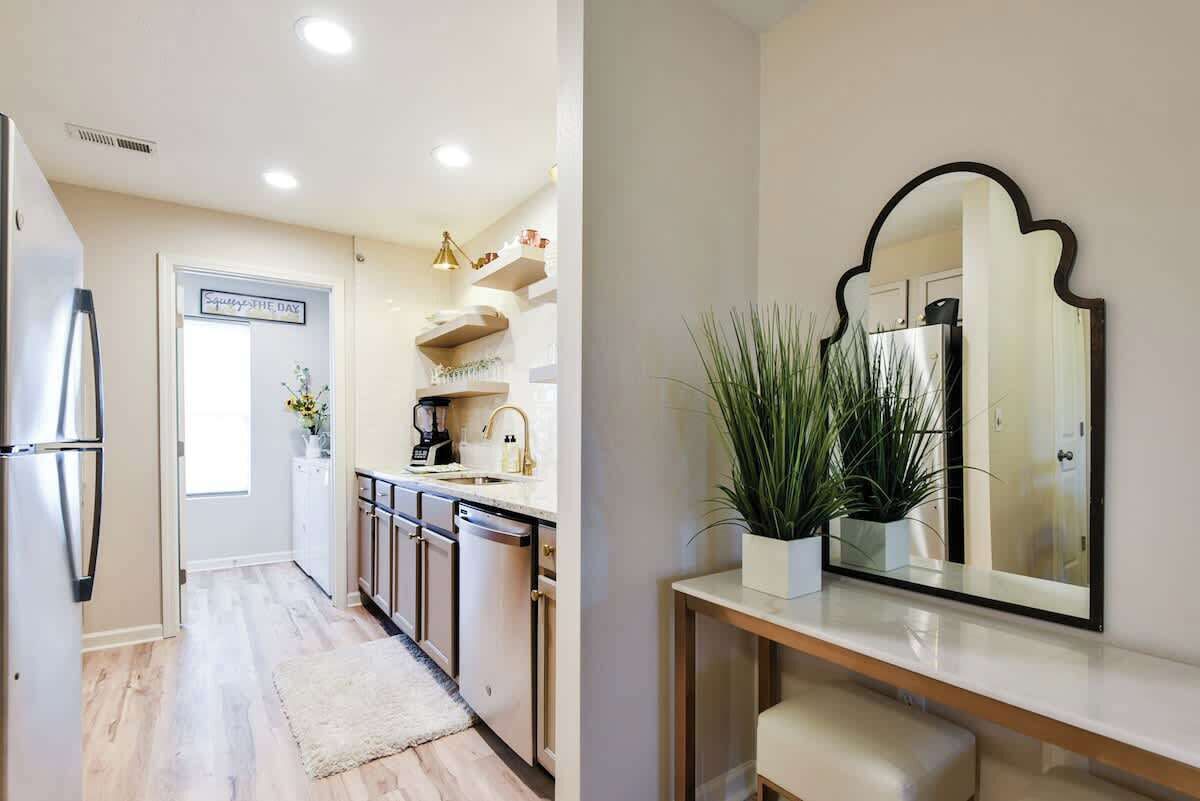 A modern kitchen with stainless steel appliances, a white countertop, and a potted plant.