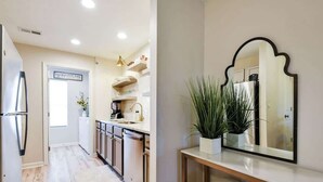 Una cocina moderna con electrodomésticos de acero inoxidable, una encimera blanca y una planta en maceta.