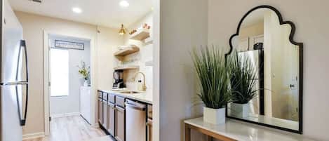 A modern kitchen with stainless steel appliances, a white countertop, and a potted plant.
