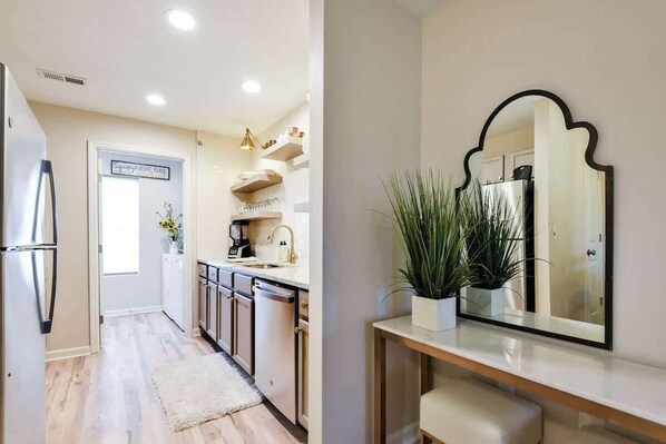 A modern kitchen with stainless steel appliances, a white countertop, and a potted plant.