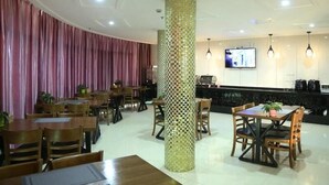A restaurant with wooden tables and chairs, a patterned pillar, and a TV mounted on the wall. - Greentree Inn Taizhou Taidong Hotel (Taizhou)