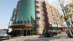 A multi-story hotel with a curved glass facade, multiple balconies, and a ground-level entrance with signage. - Greentree Inn Taizhou Taidong Hotel (Taizhou)
