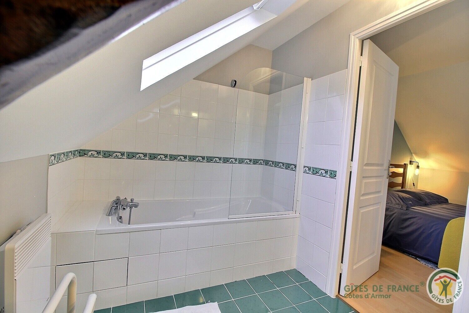 A small, compact room with a shower, a bathtub, and a bed.