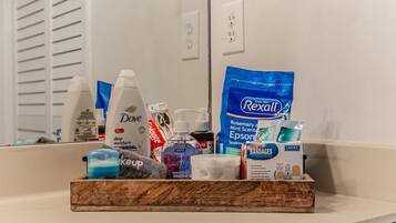 A bathroom counter with toiletries including Dove soap, Rexall Epsom salts, and a Keup bottle.