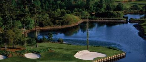 En golfbane med bunkers, et vandhinder og en bro.