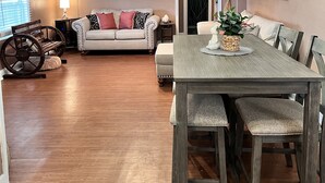 Amplia sala de estar con una mesa de comedor de madera, sillas acolchadas, un sofá y un ventilador de techo.