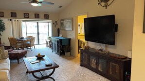 A living room with a sofa, a coffee table, a TV, a ceiling fan, and a dining area with chairs and a table. - Sunset Getaway  (Welaka)