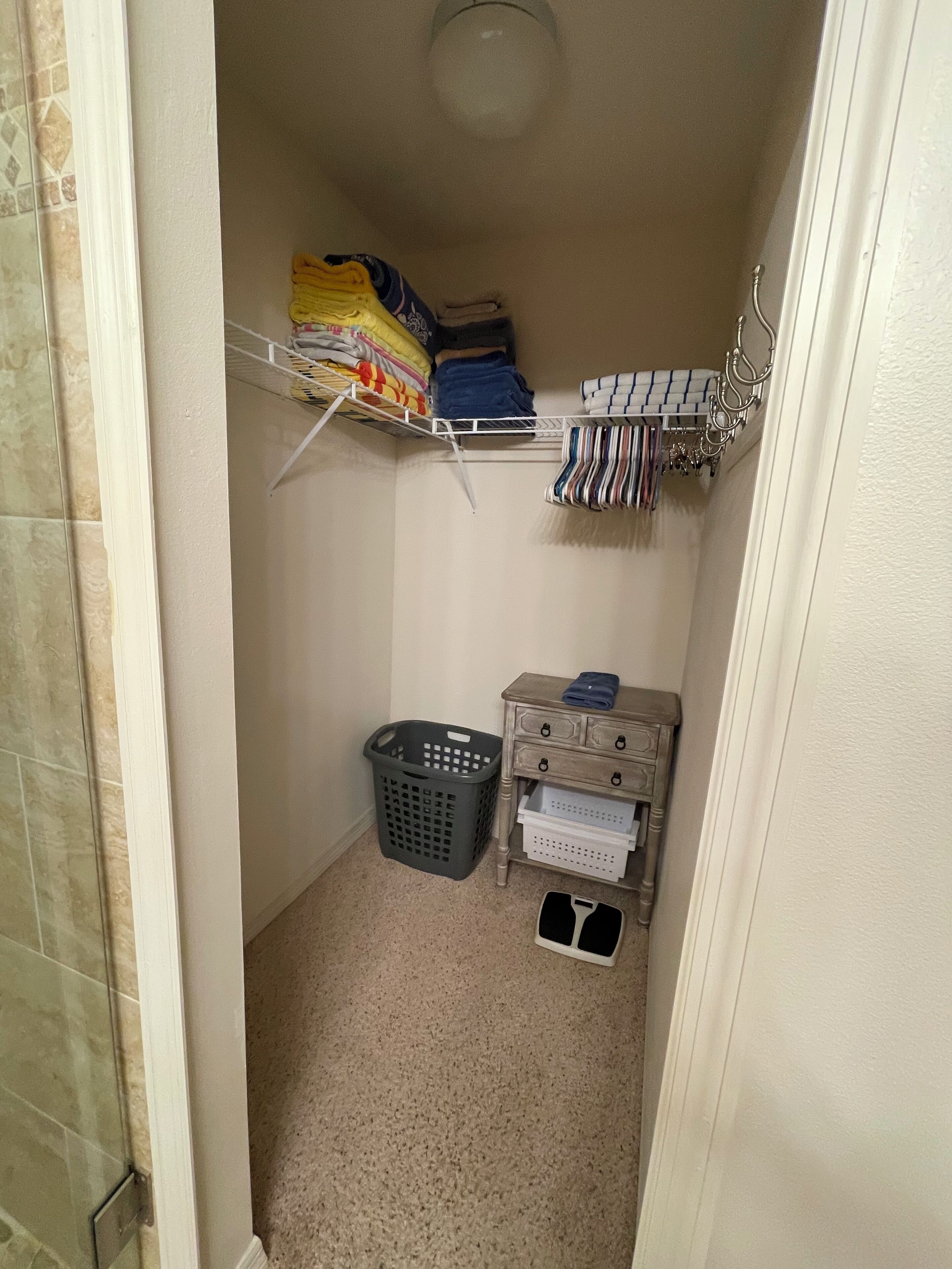 A laundry area with a washing machine, a drying rack, and a storage cabinet.