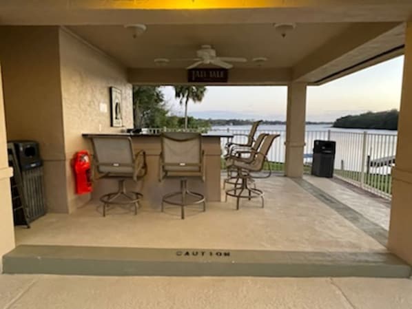 A covered outdoor area with a bar, two chairs, a fire extinguisher, and a caution sign. - Sunset Getaway (Welaka)