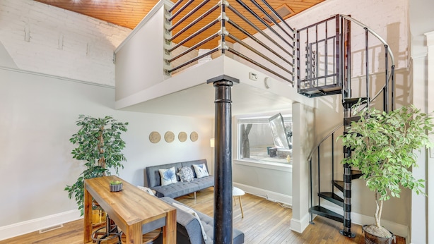 Een modern interieur met een houten trap, een eethoek en twee potplanten.