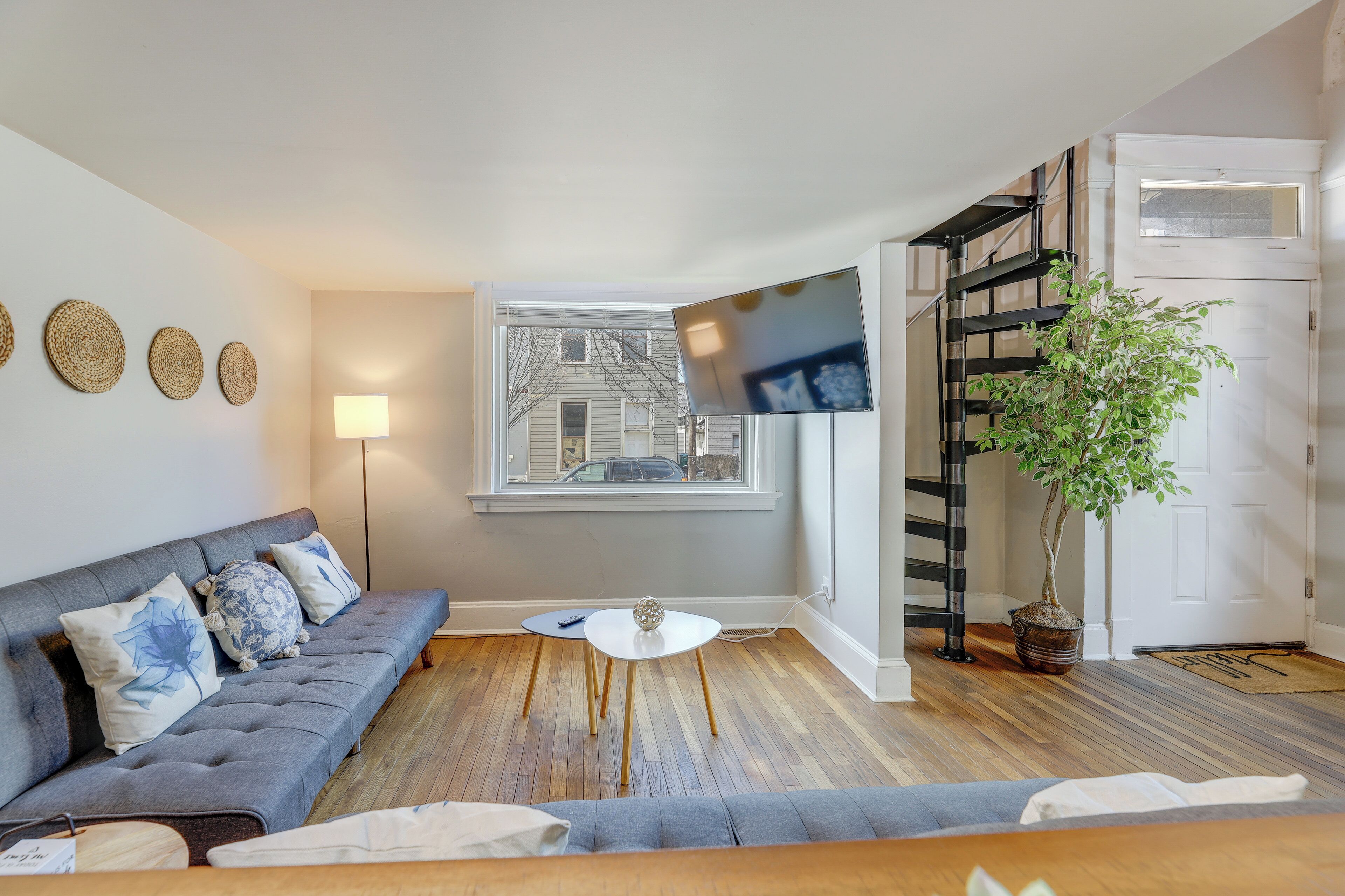 Un salon moderne avec un canapé gris, une table basse blanche et une plante en pot.