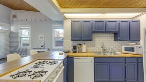 Een moderne keuken met een houten fornuis, een witte vaatwasser en blauwe kastjes.